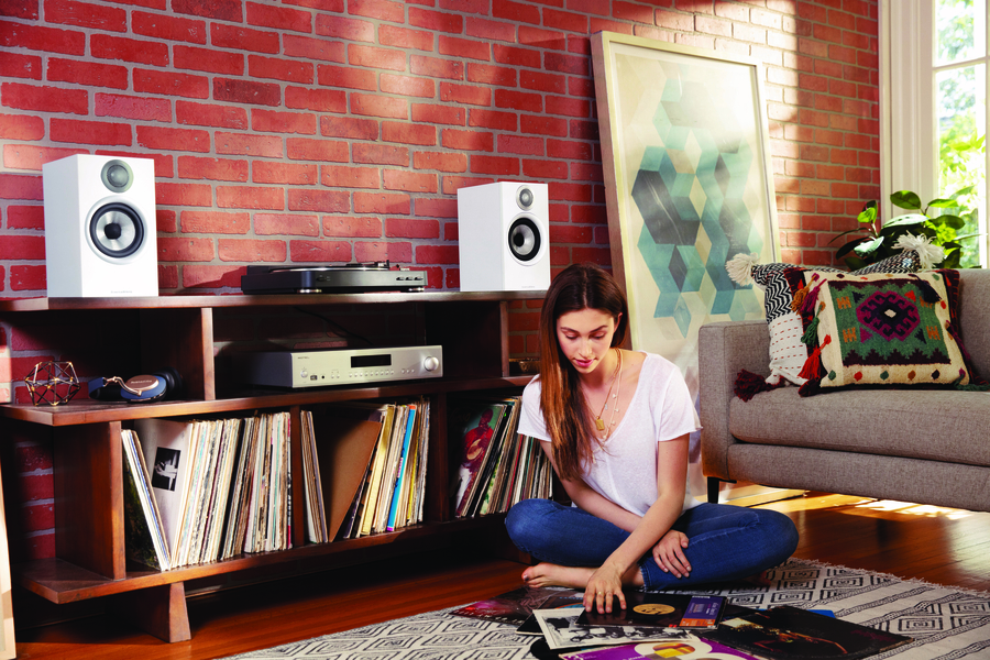 Woman looks through vinyl records while sitting on the floor in front of an AV stand