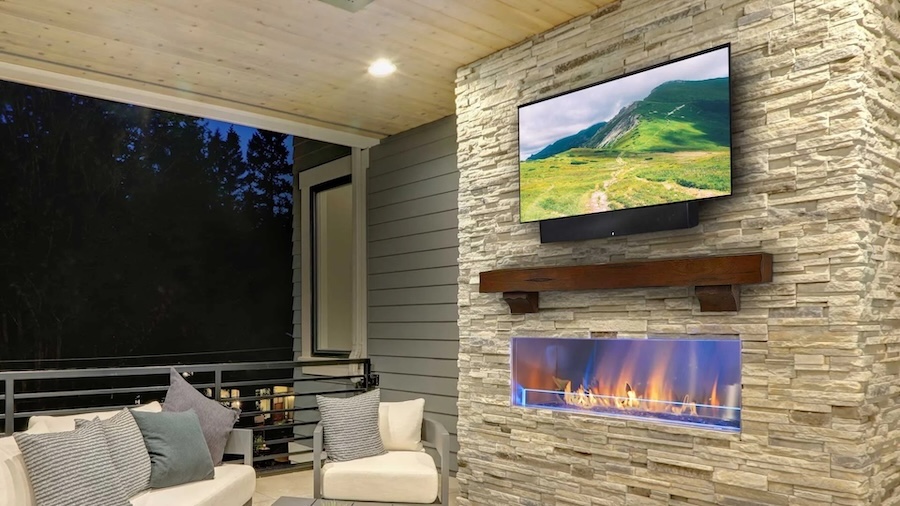 outdoor TV mounted above a fireplace on a patio.