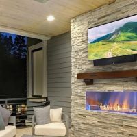 outdoor TV mounted above a fireplace on a patio.