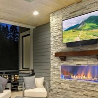 outdoor TV mounted above a fireplace on a patio.